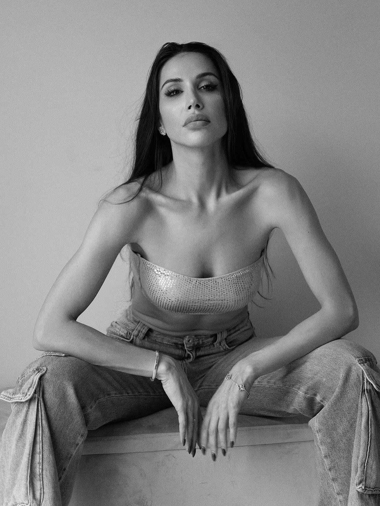 Somayeh en noir et blanc, assise face à l’objectif, bustier pailleté et jean large